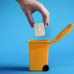 a human hand putting the application icon for file roller into an orange recycle bin against a blue background